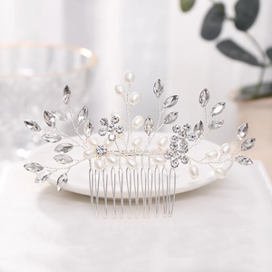 Détail du peigne à cheveux argenté avec perles et strass feuilles sur assiette blanche