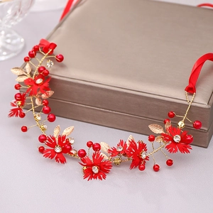 Detail of handmade bridal headband with red fabric flowers and golden leaf vines