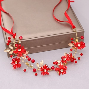 Detail of red fabric flowers and golden leaf headband with sparkling rhinestones
