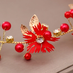 Macro detail of handmade bridal headband with red fabric flowers and golden metal leaves
