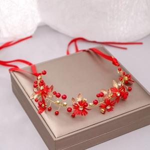 Detail of handmade bridal headband with red flowers, gold leaves and ribbon ties