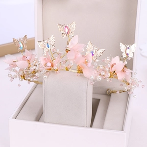 Détails d'une couronne de mariée rose avec fleurs en tissu, perles et papillon doré