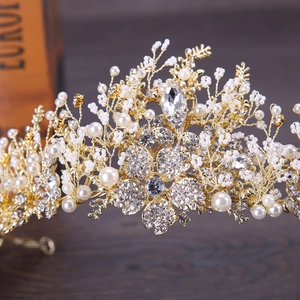 Close-up of handmade bridal tiara with gold finish, white pearls and crystal flowers