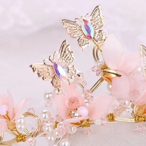 Détail de la monture dorée avec fleurs en tissu, perles blanches et papillons en cristal