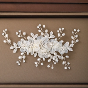 Dettaglio ravvicinato di pettine per capelli da sposa con fiori di chiffon e perle