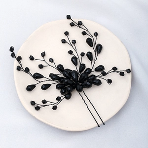 Macro shot of black beaded wedding hair pin with faceted crystals on a ceramic plate