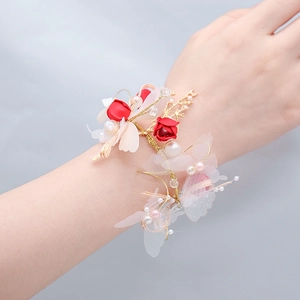 Gros plan de roses en soie rouge et d'accents dorés sur un corsage de poignet de mariée