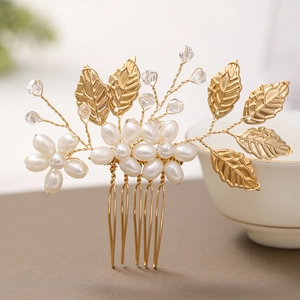 Détail d'un peigne à cheveux de mariée fait main avec feuilles dorées et perles