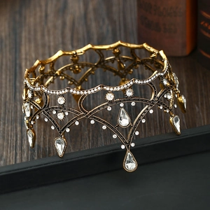 Detail view of retro gold crown featuring hollow metal carvings and white crystals