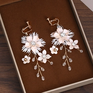 Détail de boucles d'oreilles clips de mariée avec pompons fleuris et cristaux roses