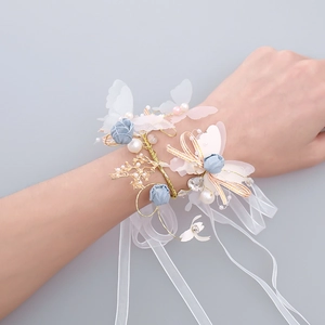 Détail du bracelet floral fait main avec fleurs bleues, ailes de papillon et perles