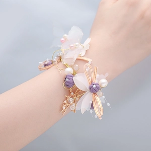 Détail de corsage de poignet de mariée avec fleurs mauves, perles et papillon
