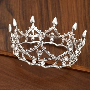 Elegant silver baroque bridal crown with white crystals on a rustic dark wooden base