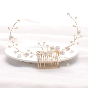 Detalle de peineta de novia con ramas de hilo dorado, perlas y flores blancas artesanales