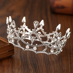 Close-up of silver baroque bridal crown with intricate crystals on dark wood surface