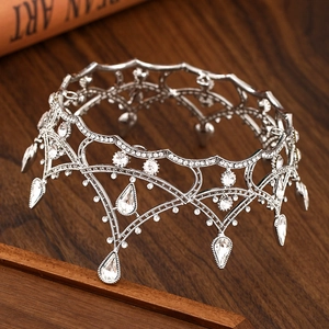 Detailed side view of vintage silver crown with teardrop crystals on wood surface