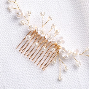 Detalle del peine de novia artesanal con flores blancas, perlas y alambre dorado