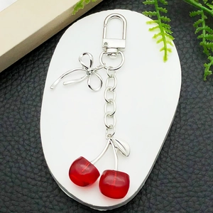 Creative red cherry keychain with silver bow and resin pendants on white plate