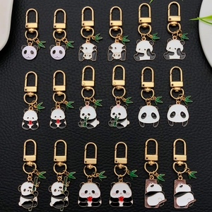 Collection of 18 cute panda enamel keychains with bamboo charms on black leather background