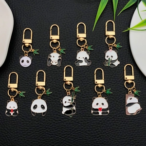 Set of 9 cute panda enamel keychains with bamboo leaves on black leather background