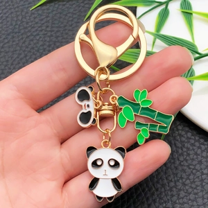 Close-up of golden metal panda keychain featuring bamboo charm and enamel finish