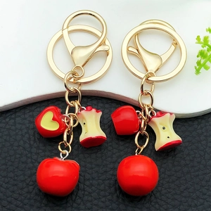 Cute resin red apple keychains with gold hardware on black and white background