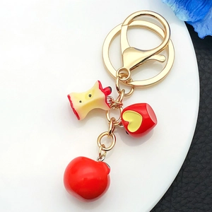 Detail of red apple resin pendant keychain with gold metal clasp and bite mark detail