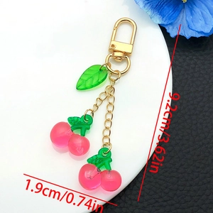 Close-up of pink resin cherry keychain with green leaves and gold chain dimensions