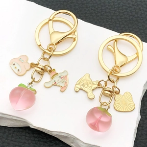 Cartoon peach keychain with cute resin puppy and peach charms on a golden metal ring