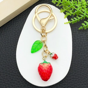 Détail de porte-clés fraise 3D réaliste en résine avec anneau doré et feuille verte