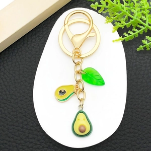 Detail showing creative avocado keychain with golden clasp and 3D fruit pendants
