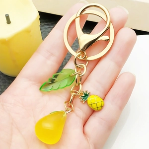 Handmade fruit keychain with yellow pear charm and pineapple pendant on a gold metal chain