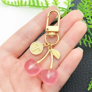 Kirsch-Schlüsselanhänger in Rosa mit goldenem Blatt und T-Anhänger, handgehalten
