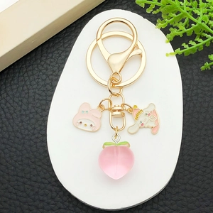 Close-up of golden keychain with Cinnamoroll, My Melody charms and pink resin peach