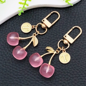 Schicker rosa Kirsch Schlüsselanhänger mit goldenem Buchstaben T auf schwarzem Leder
