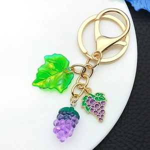 Dettaglio di un portachiavi a forma di uva viola in resina con foglie e anello d'oro