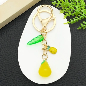 Detail of fruit keychain with yellow pineapple and pear resin charms on gold ring
