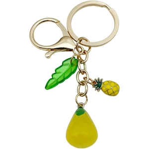 Golden keychain with resin pineapple fruit and green leaf pendants on white background