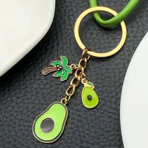 Close-up of golden palm tree and avocado enamel pendants on a circular metal keyring