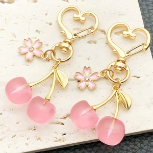 Detail of pink resin cherry keychain with golden heart clasp and crystal floral charm