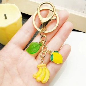 Golden keychain with resin lemon banana and green leaf charms held in hand