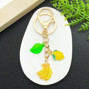 Close-up of resin fruit key ring with enamel green leaf, lemon, and banana charms