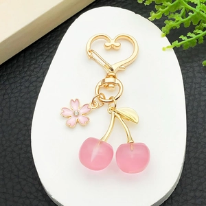 Detail of pink cherry keychain with gold heart-shaped clasp and floral rhinestone accents