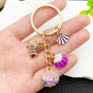 Porte-clés océan doré avec pendentifs étoile de mer et coquillages colorés en main