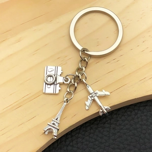 Détail d'un porte-clés de voyage argenté avec pendentifs appareil photo, Tour Eiffel et avion