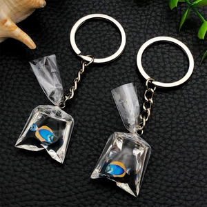 Set of two realistic resin blue tang fish bag keychains on a black textured background