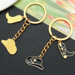 Close-up of gold cowboy hat and boots keychain with black enamel star details
