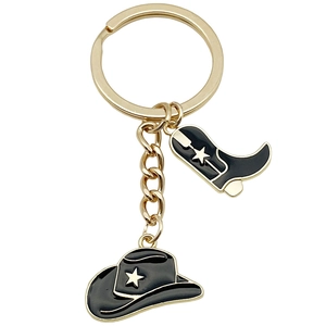 Golden cowboy boot and hat keychain with black enamel finish and white star details