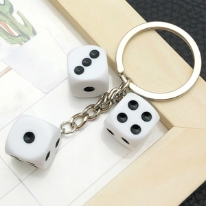 Llavero creativo con dados de resina blanca y anillo de plata sobre fondo de cuero negro
