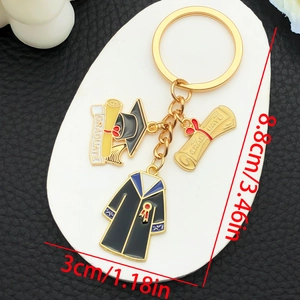 Close-up of graduation keychain with black cap and gown charms on white display